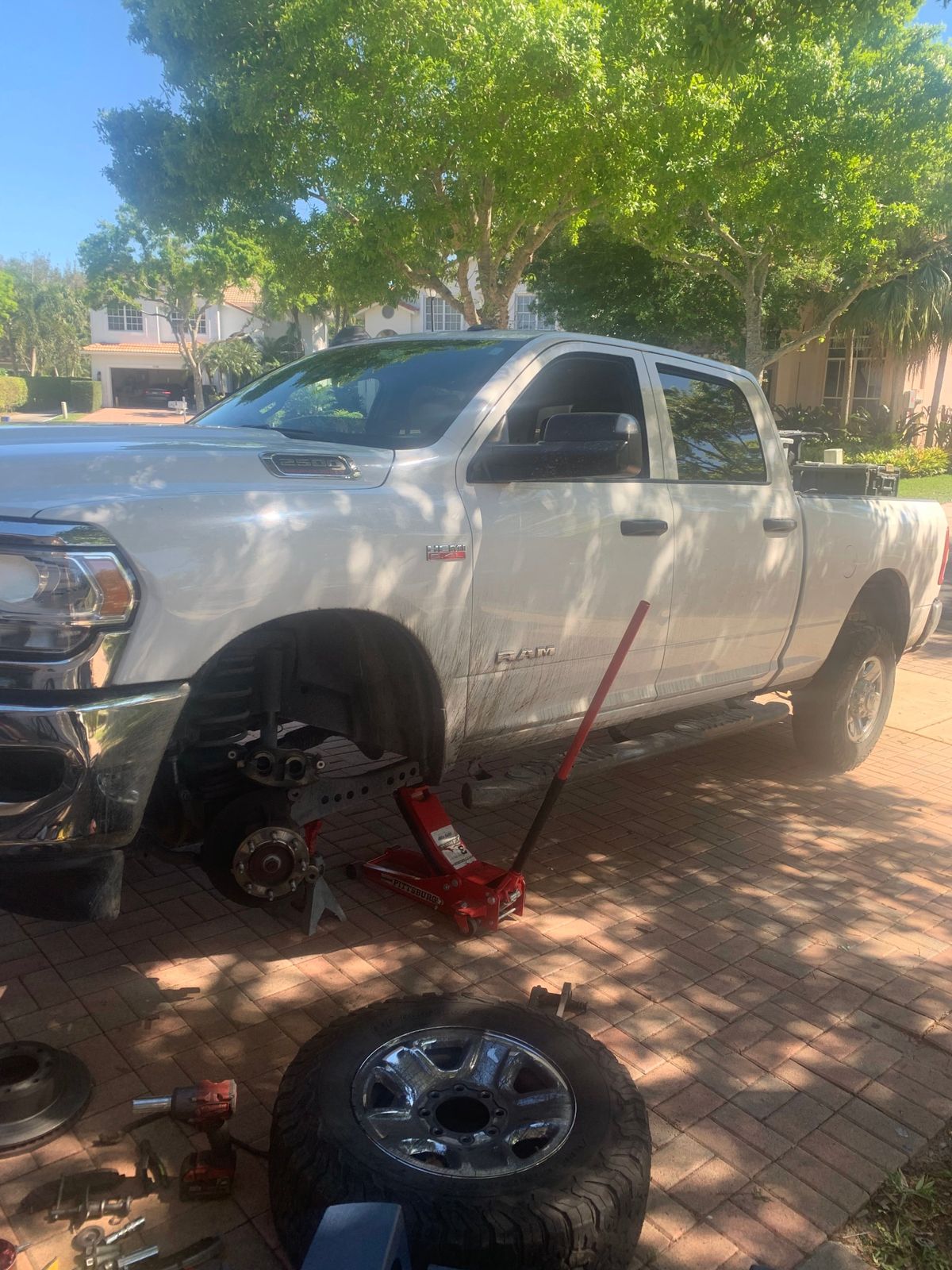 Front wheel off a Ram 2500 in a driveway, hub exposed for a brake service