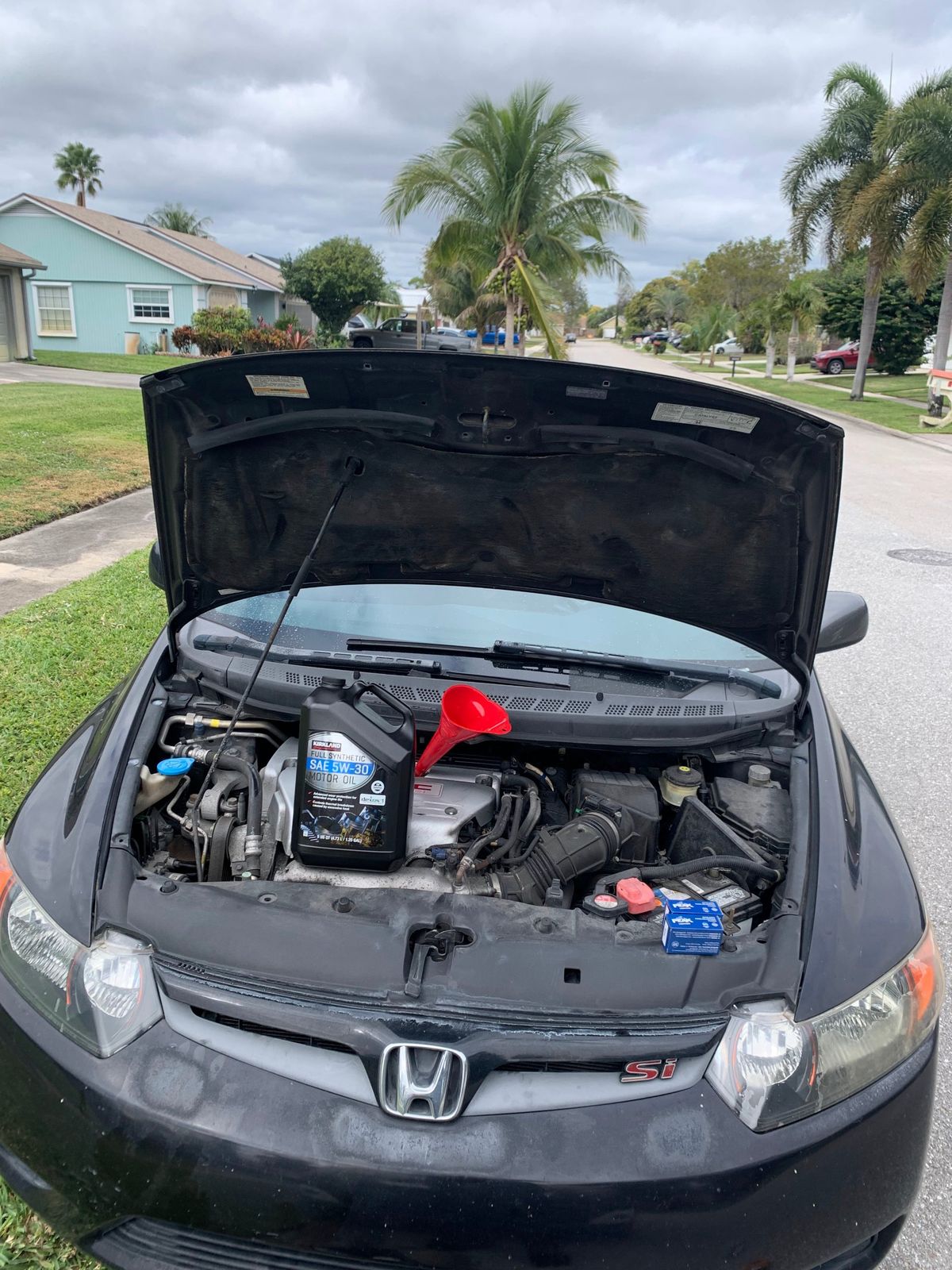 Mobile oil change underway on a Honda Civic parked on a residential street